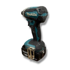 Makita cordless drill with 18V battery and belt clip, shown from the side, used and dusty.
