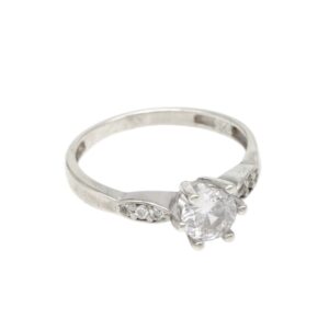 Silver ring with a large round-cut center diamond held by prongs, accented by smaller stones on the band against a white background.