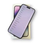 Smartphone resting on its box, screen showing a list of languages (e.g., Ελληνικά, Română, Magyar).