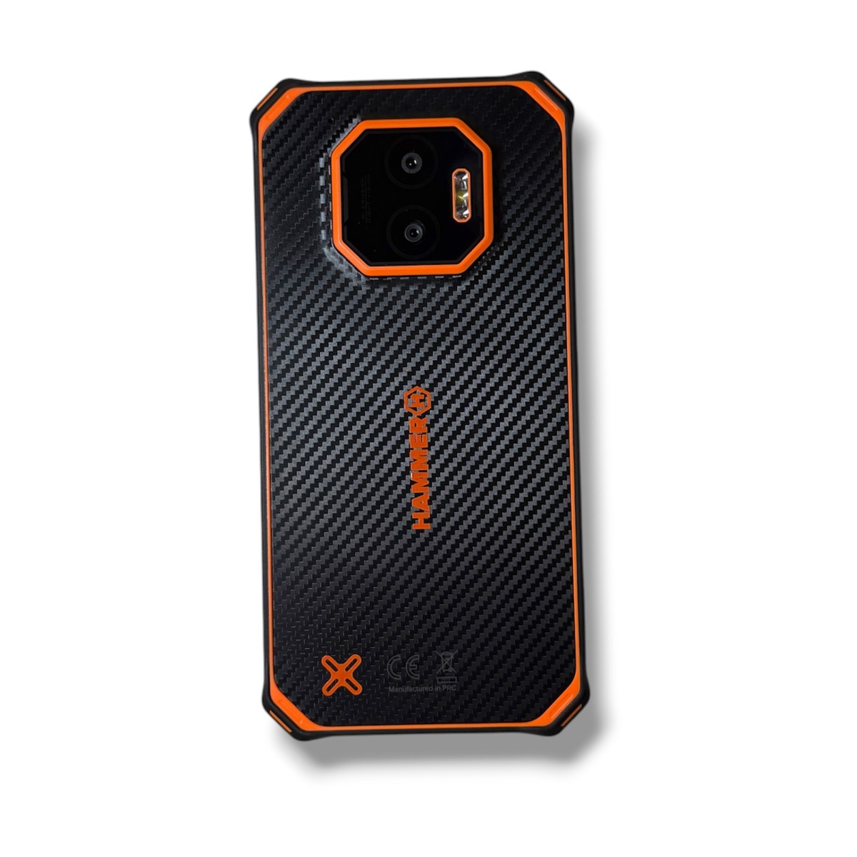 ab32df4906ce45a0e4eddc4ef6d44b0ejpg - Mezola OÜ Rugged black smartphone back with orange bumper and hexagonal camera housing outlined in orange on a carbon-fiber pattern back, HAMMER logo visible.