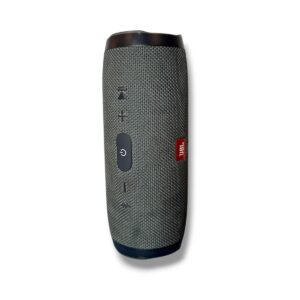 JBL portable speaker in gray fabric with a circular power button and volume controls along the side; cylindrical design with a red JBL logo.