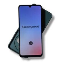 Smartphone showing a Xiaomi HyperOS splash screen with a gradient blue-pink background and a circular arrow button on the homescreen