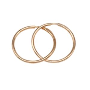 Pair of thin gold hoop earrings intertwined and overlapping against a white background